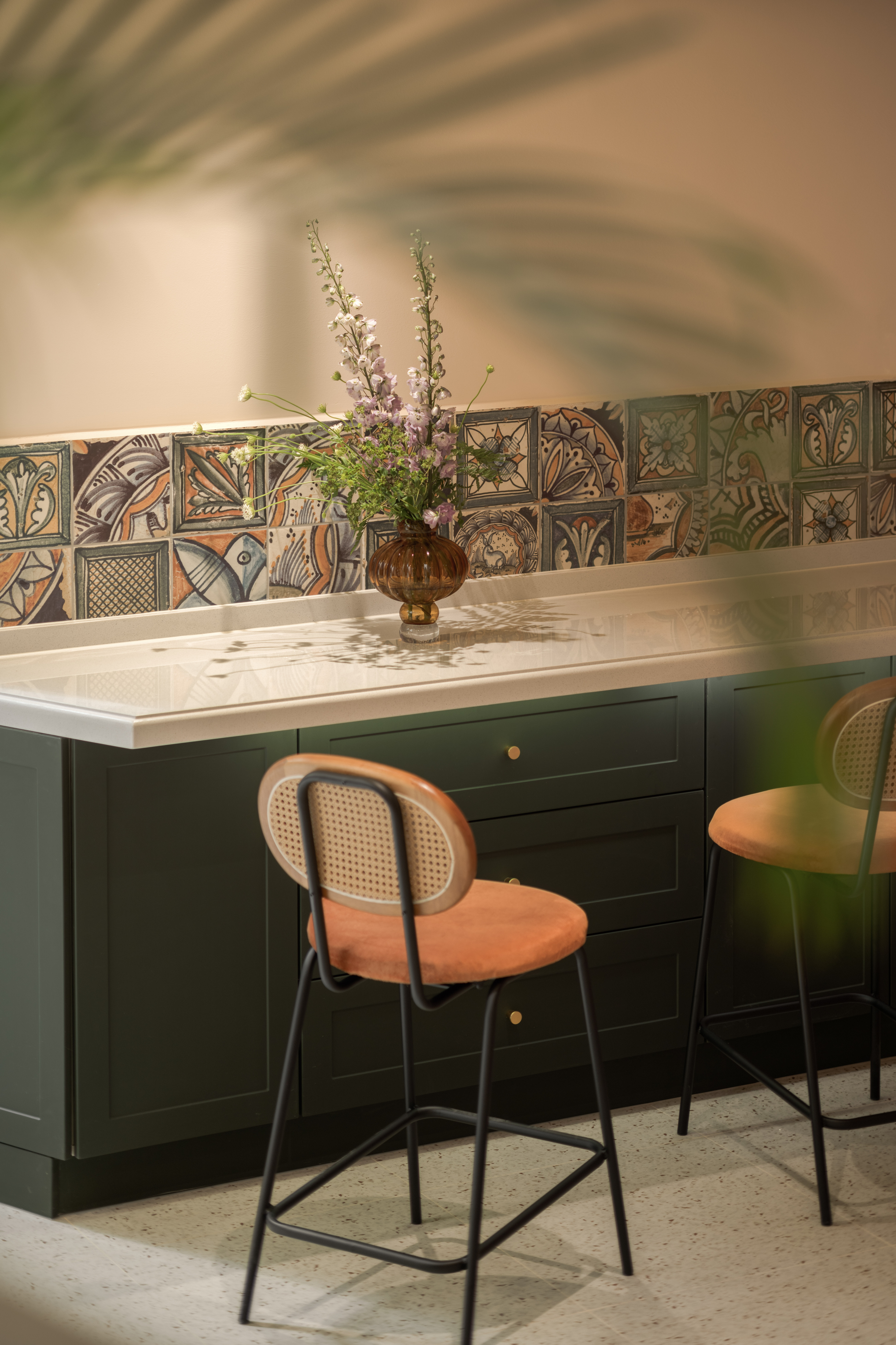 Green kitchen with patterned-tile backsplash by One Home Interiors