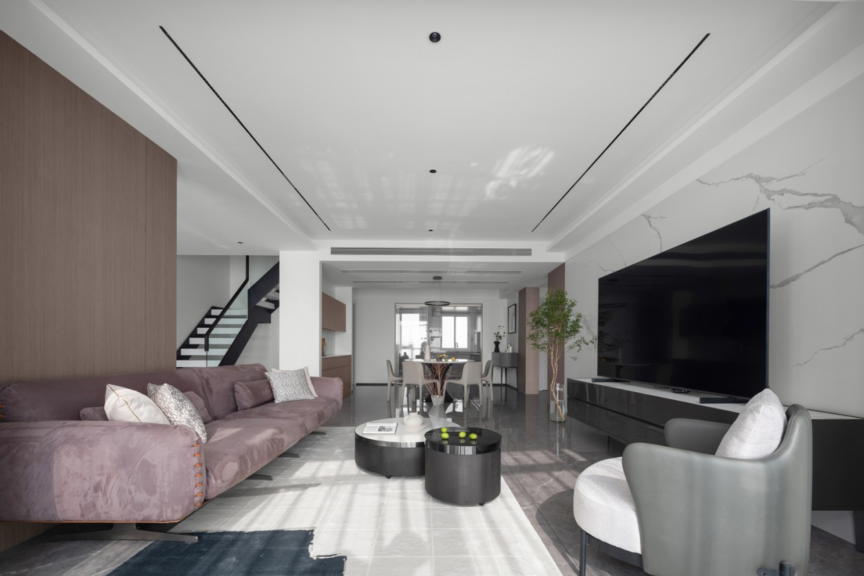 Open living and dining space with marble TV wall, walnut console and staircase
