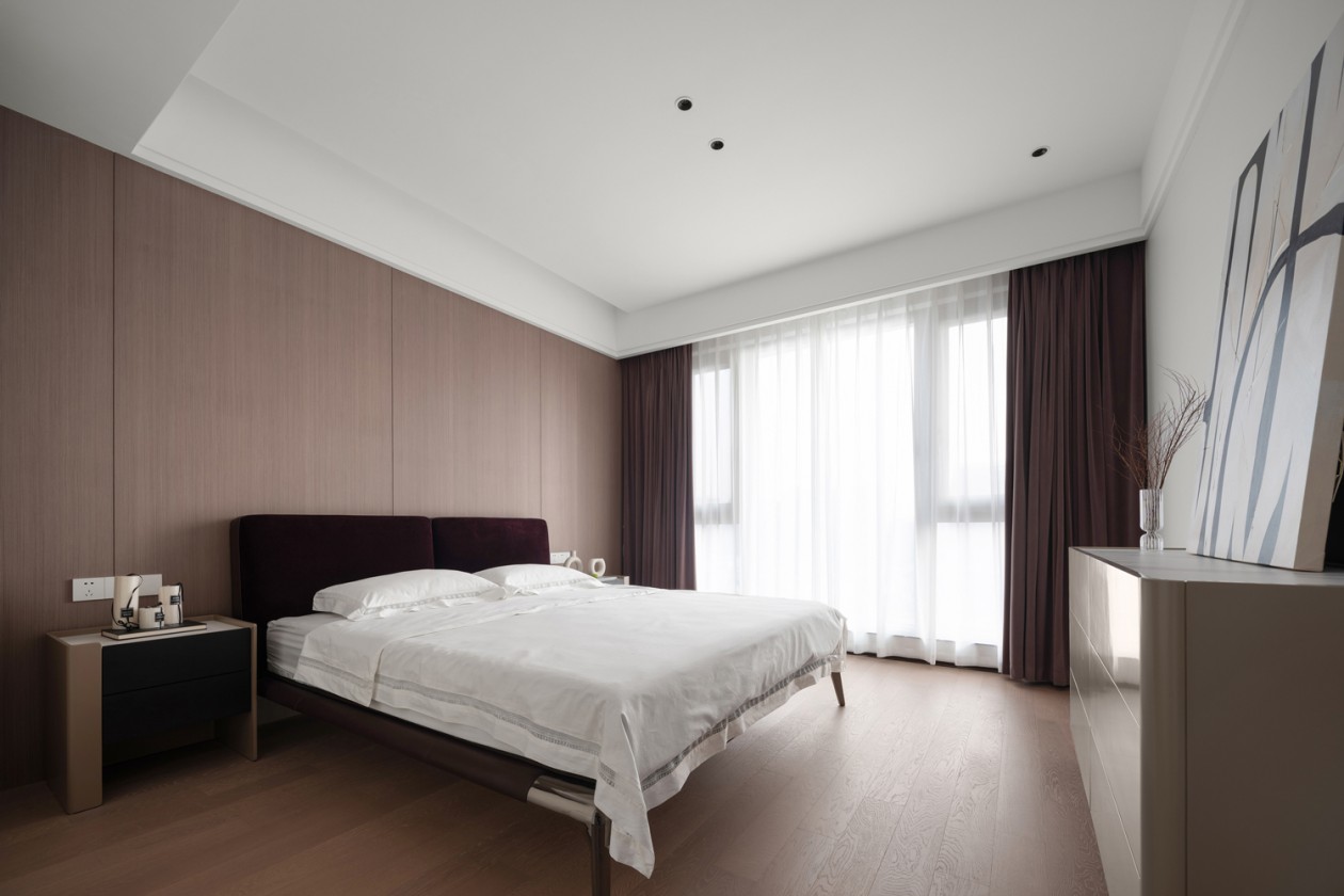 Master bedroom with burgundy velvet headboard and warm oak wall panelling