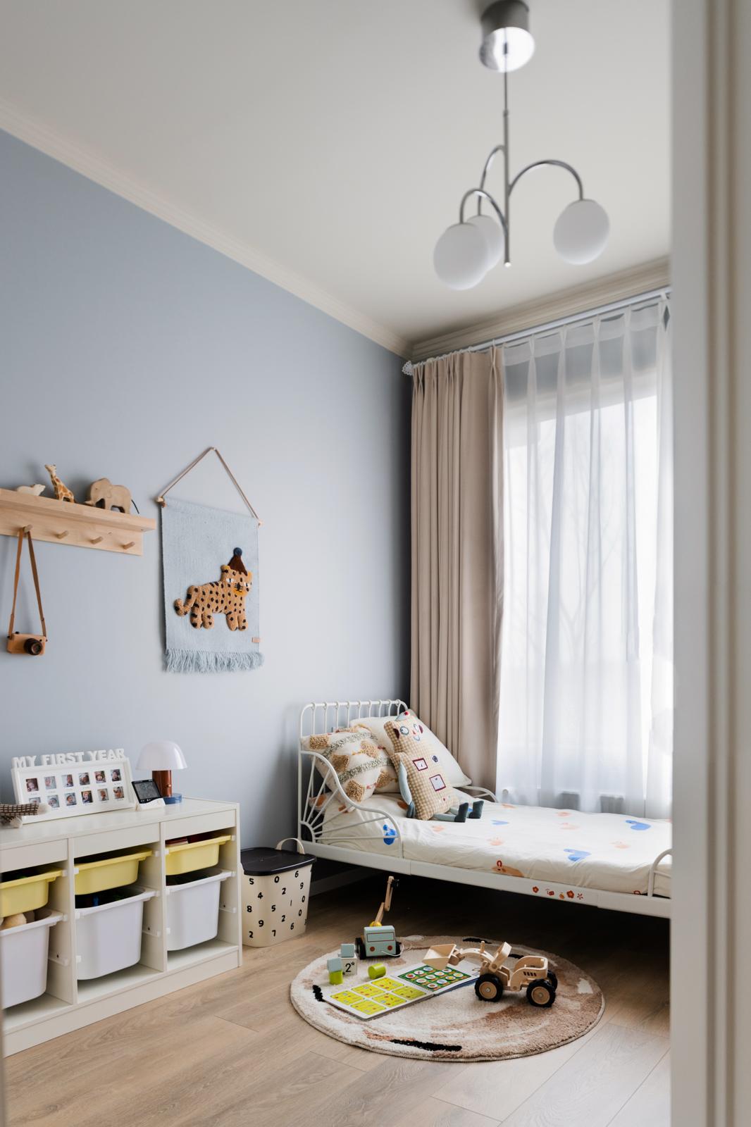 Children's bedroom with soft blue walls, toddler bed and play zone