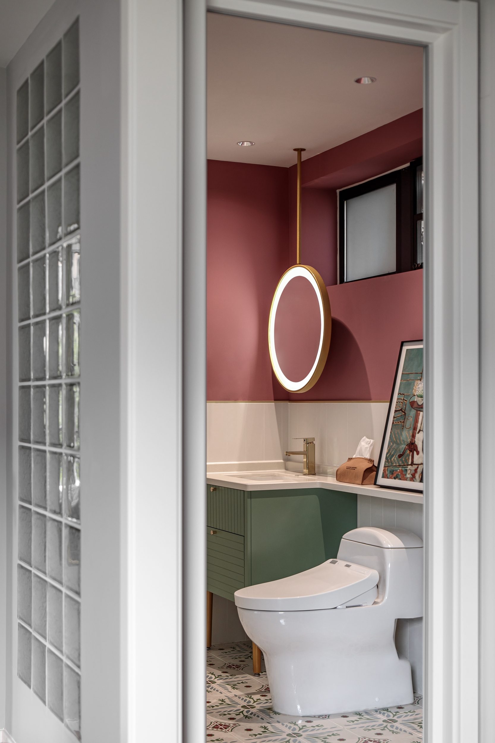 Rose pink ensuite bathroom with round backlit mirror and green vanity